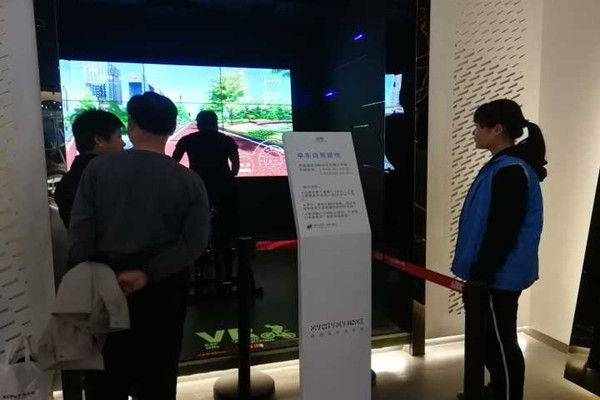 志愿者指导参观者进行VR单车自驾的体验